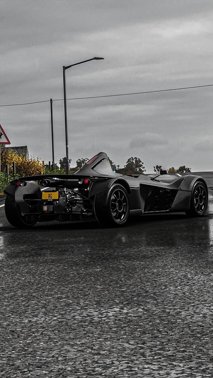 Black sports car rear view on wet asphalt during rain with visible mechanical parts and yellow license plate.