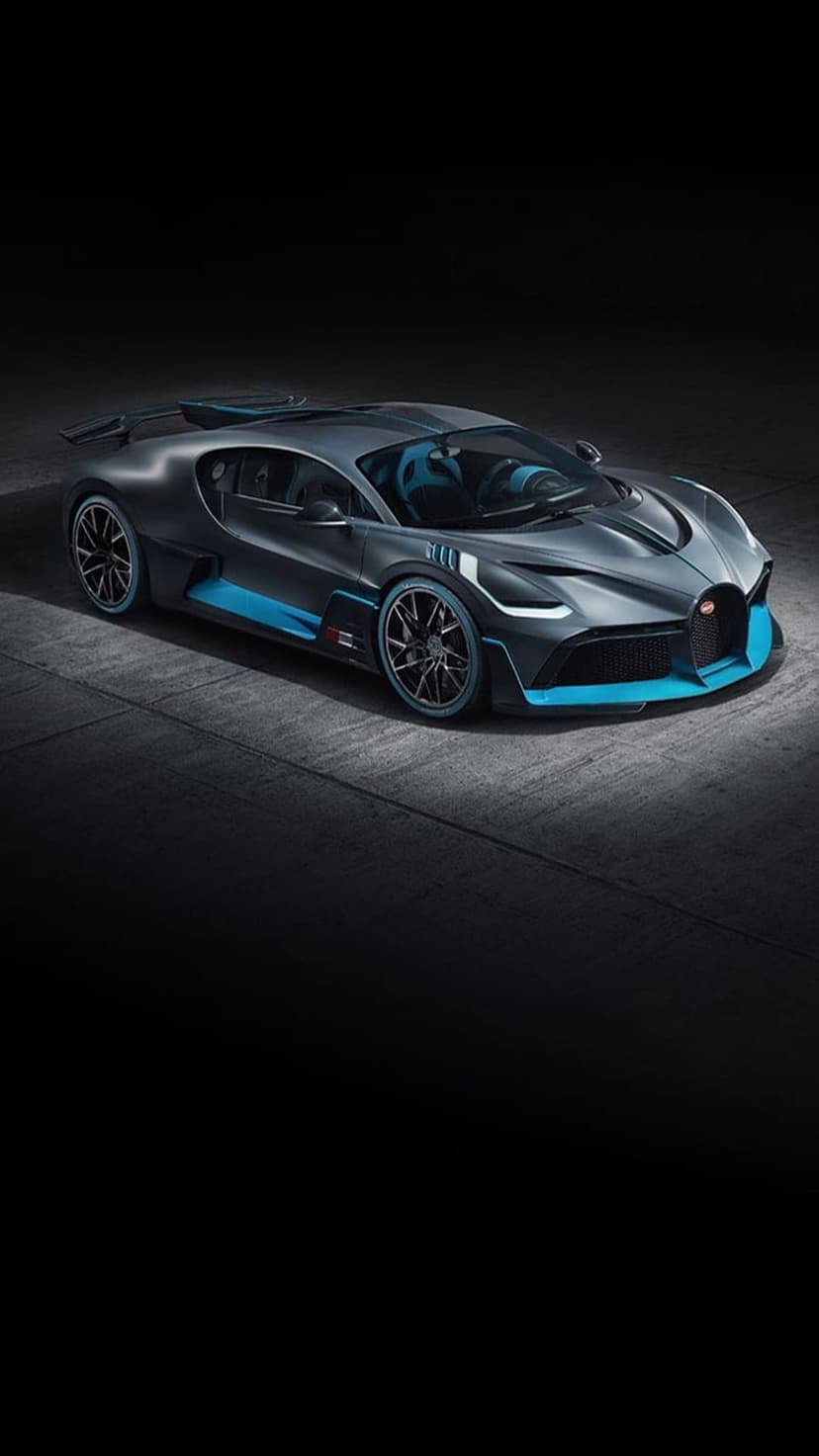Bugatti Divo hypercar in dark gray with blue trim highlights parked in a dramatic low-light studio environment.