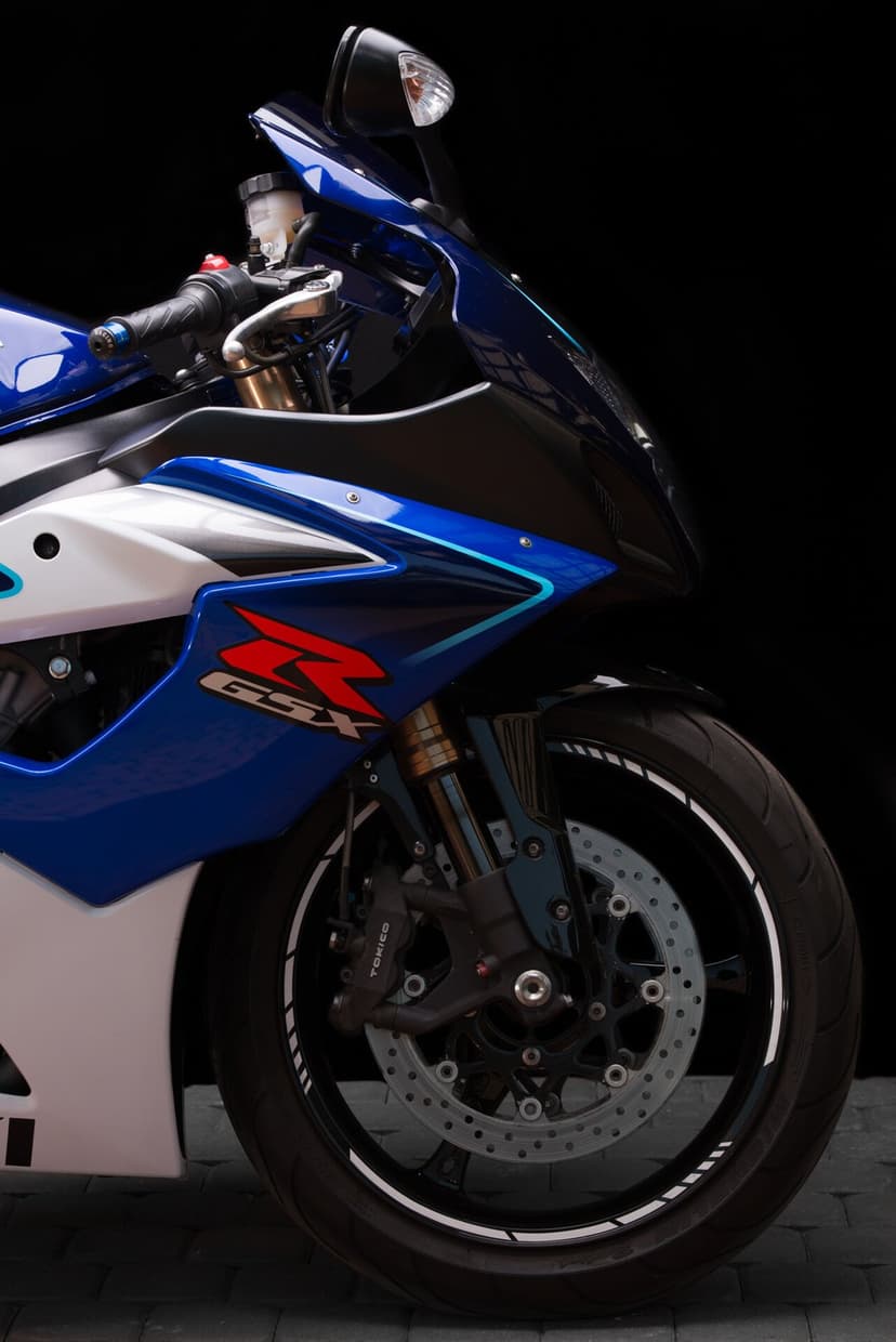 Detailed front view of a blue and white Suzuki GSX-R motorcycle with Tokico brakes on a black background.