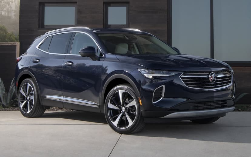 Dark blue Buick Envision SUV parked on a concrete driveway in front of a modern wood-paneled house.