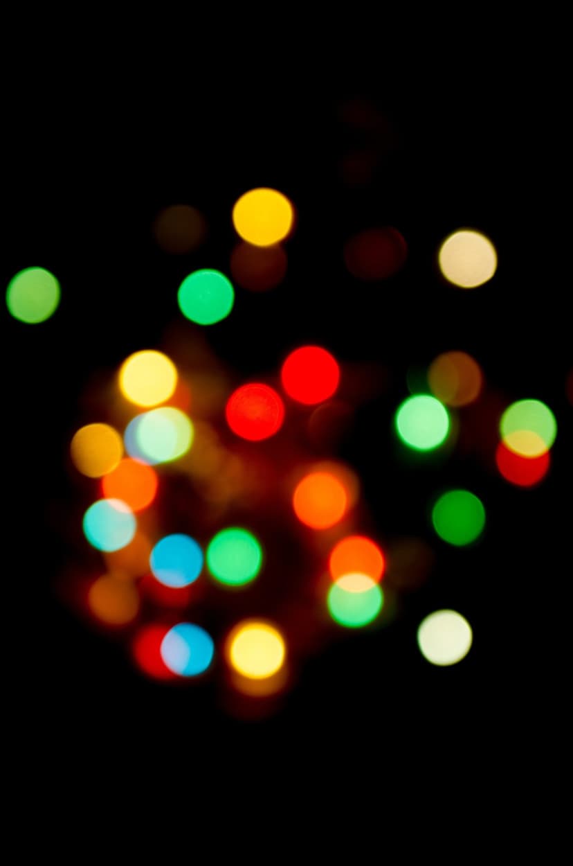 Colorful out-of-focus light circles in green, red, and blue glowing on a dark vertical abstract background.