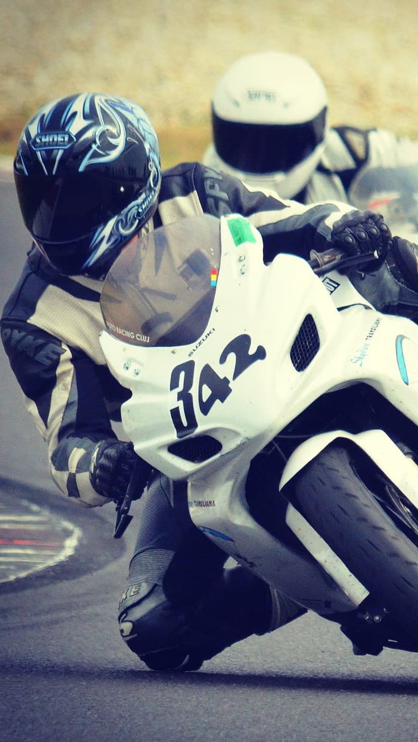 Motorcyclist in a blue helmet leans a white sportbike marked 342 into a turn on a paved racing circuit.