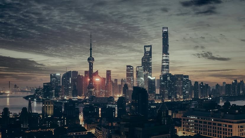 Oriental Pearl Tower and Pudong skyscrapers glow against a purple twilight sky reflecting in the river water.