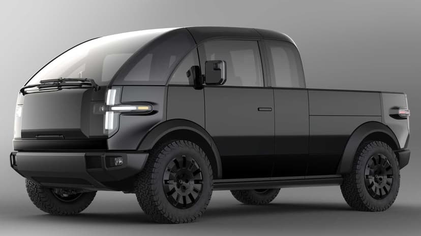 Matte black electric pickup truck with T-shaped headlights and off-road tires on a neutral grey studio background.