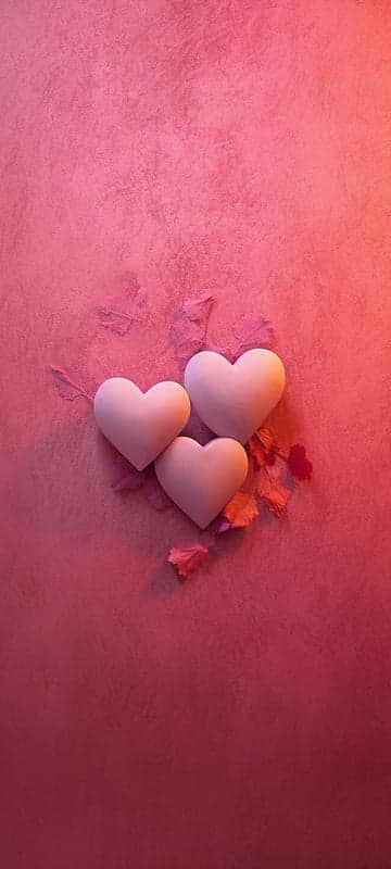 Three white hearts on a pink textured background