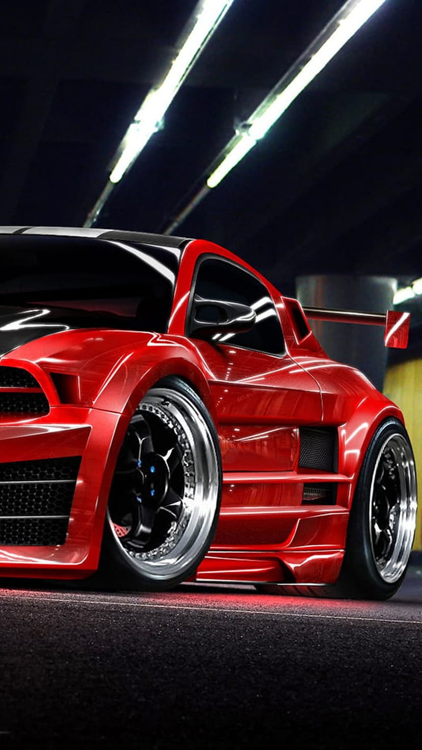 Red sports car with wide body kit and chrome rims parked in a dark garage under bright fluorescent ceiling lights.