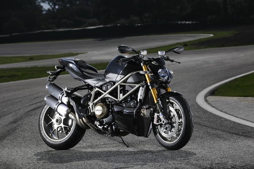 Black Ducati Streetfighter S motorcycle with gold forks parked on a winding asphalt racing circuit.
