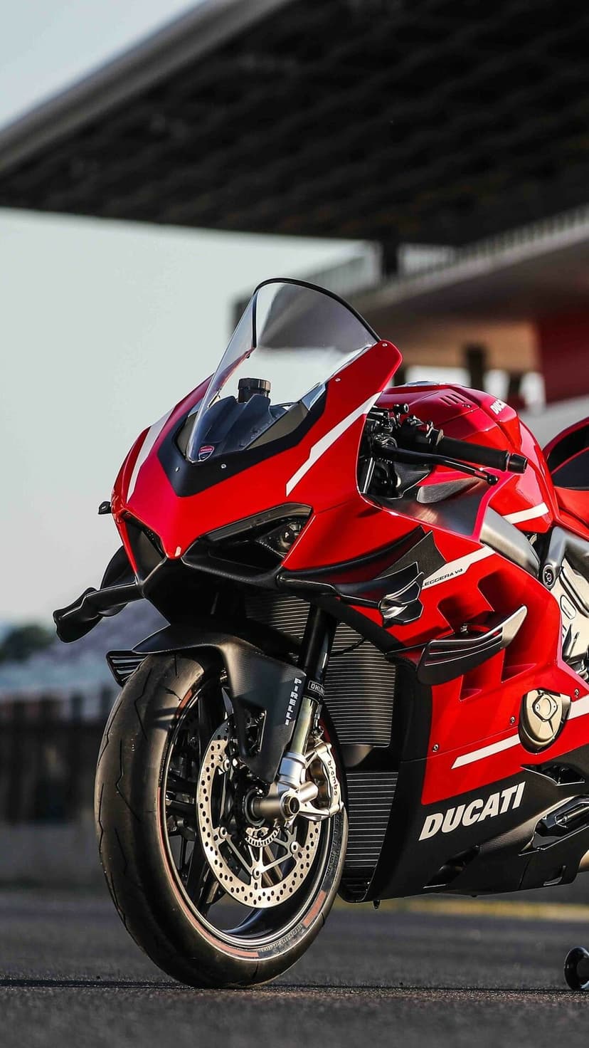 Front view of a red Ducati Superleggera V4 with carbon fiber wings and Brembo brakes on a racetrack.