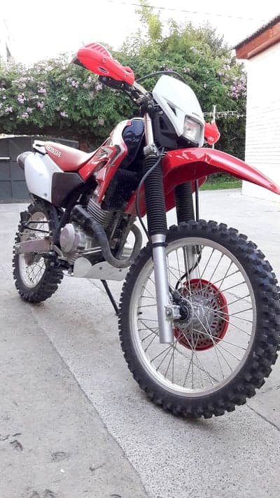 Red Honda Dirt Bike with Knobby Tires on Pavement