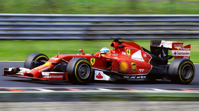 Red Ferrari Formula 1 car racing on a track with motion blur streaks and Shell sponsorship logos visible.