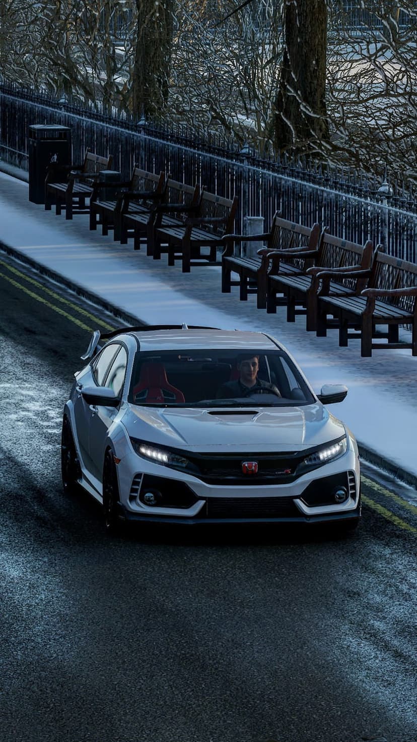 White Honda Civic Type R with red seats drives on a wet road past snow-covered park benches and frosted trees.