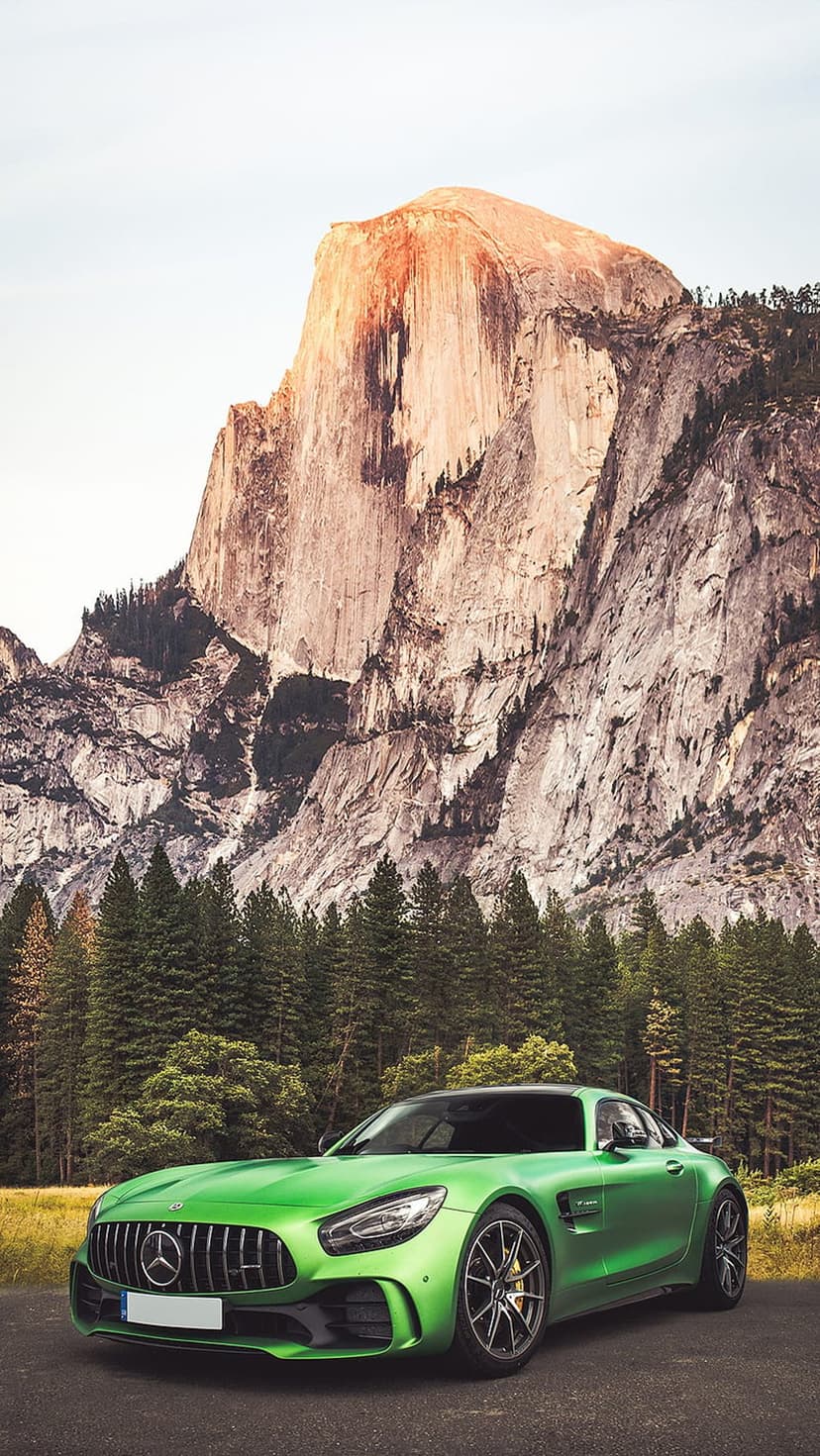 Green Mercedes AMG GT parked on a Yosemite road with Half Dome and pine forests under golden hour light.