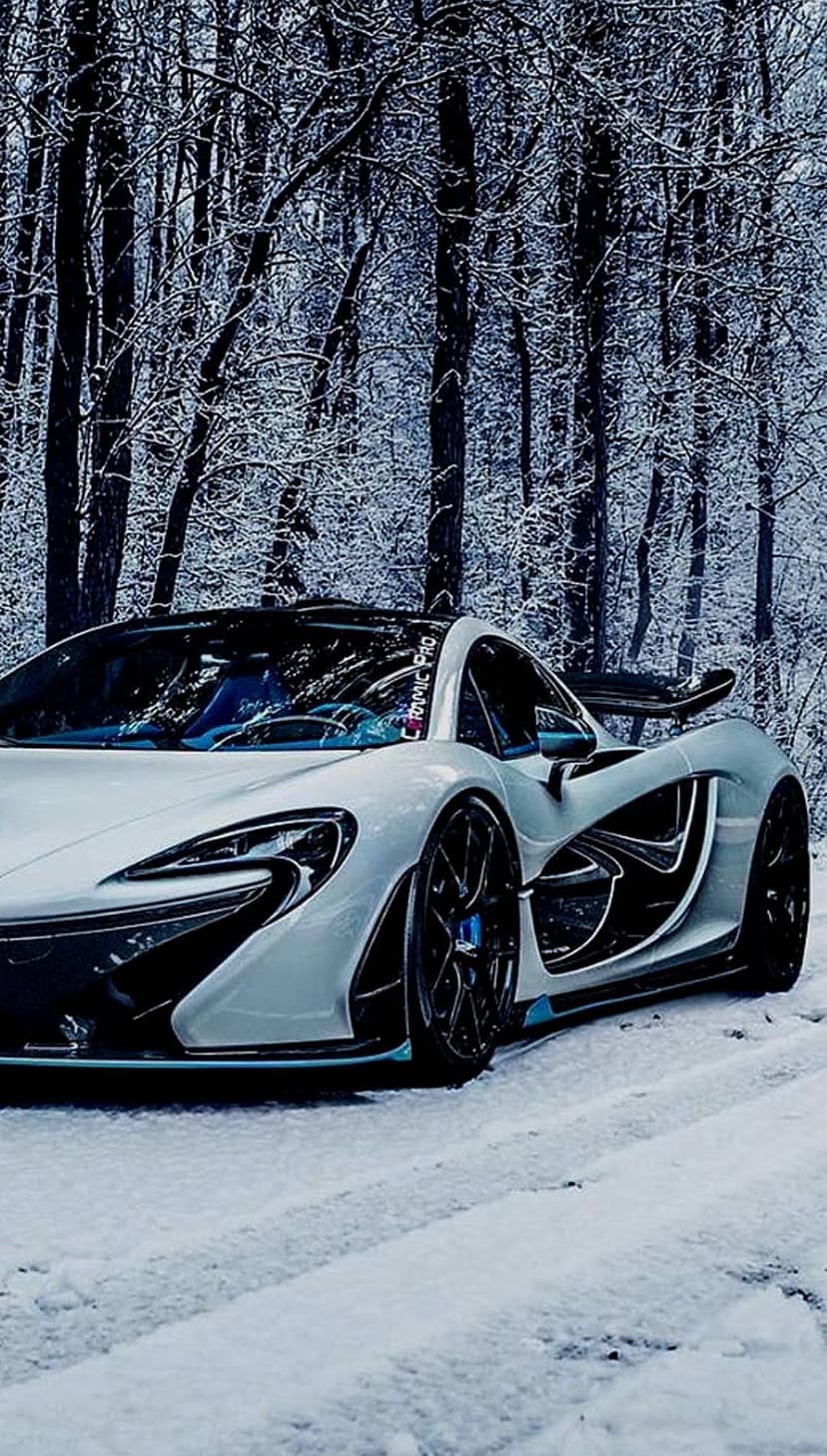 White McLaren P1 supercar parked on a snow-covered forest road during winter with frost-laden evergreen trees.