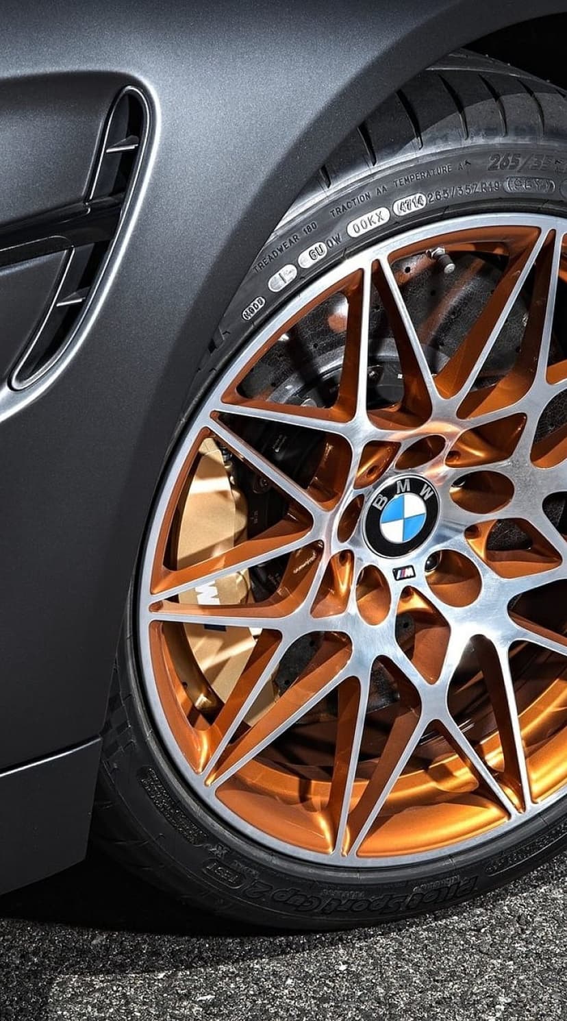 BMW M alloy wheel featuring silver spokes, copper accents, and bronze brake calipers on a performance tire.