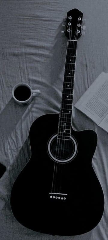 Acoustic Guitar, Coffee, and Book on a Bed