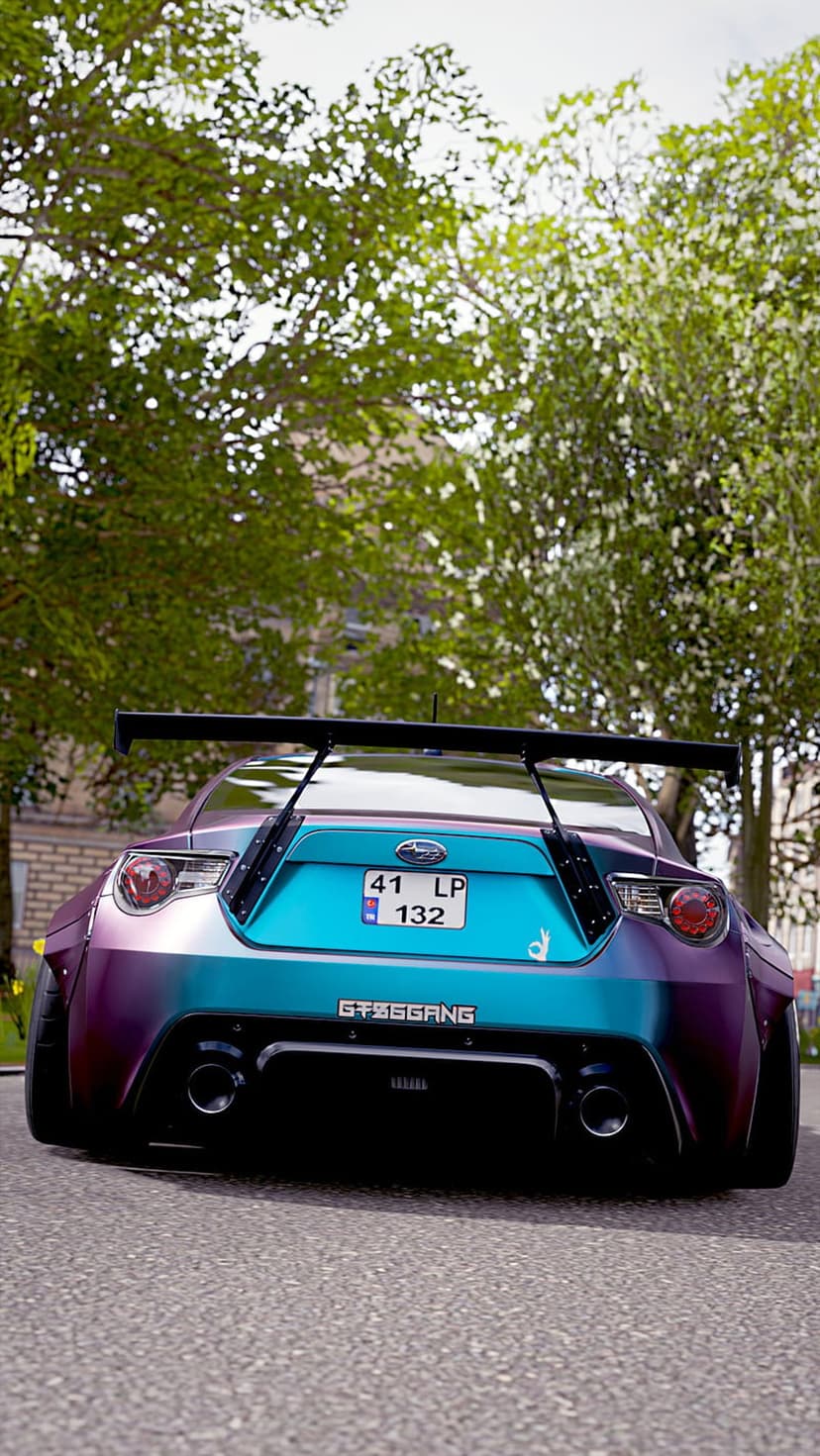 Subaru BRZ rear view features iridescent color-shifting paint and a large racing spoiler on an asphalt road.