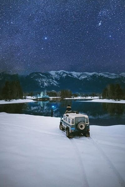Winter Night Sky and Snowy Landscape with Vehicle