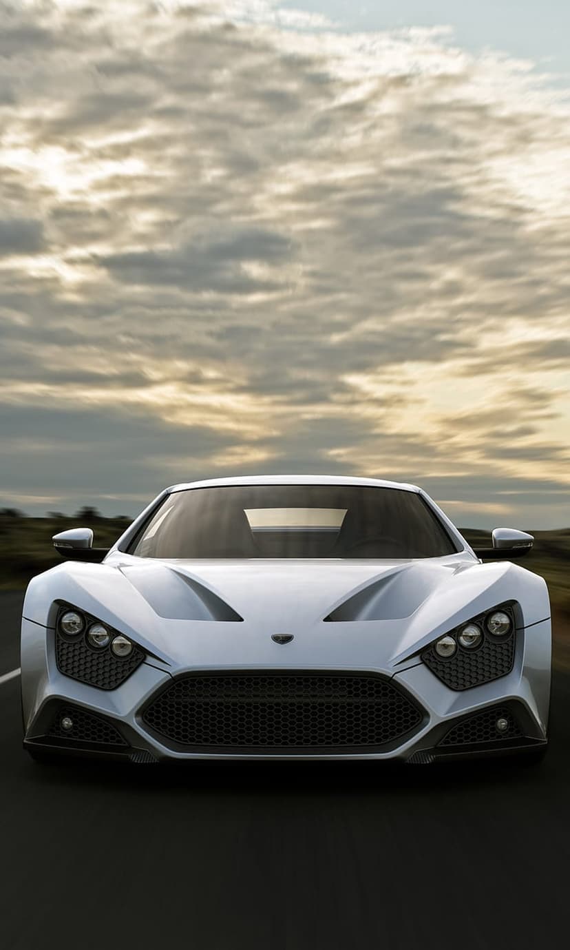 Zenvo ST1 white hypercar drives on a road under a grey overcast sky with motion blur on the asphalt.