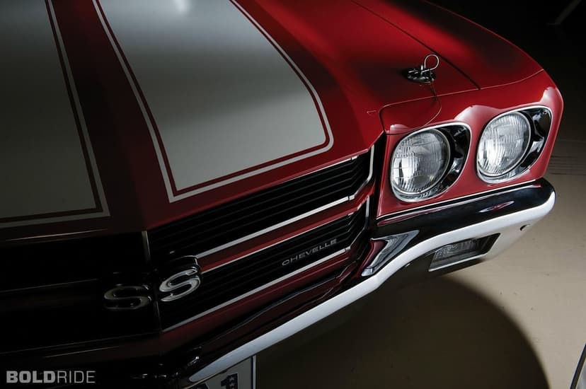 Red 1970 Chevelle SS featuring white racing stripes, chrome grille details, and circular headlights in close-up.