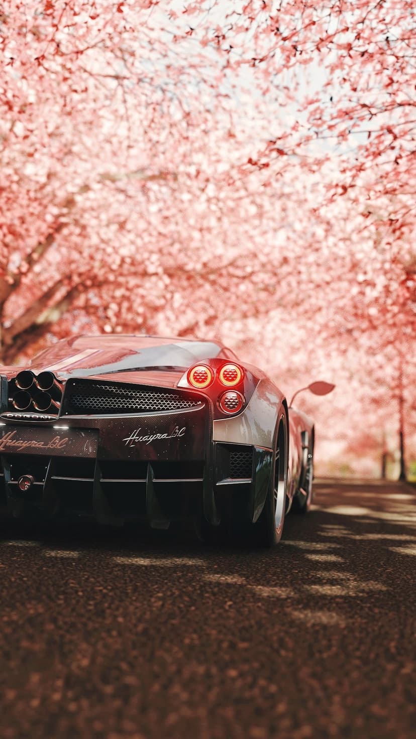Pagani Huayra BC rear end showing quad exhausts and taillights amidst a canopy of pink cherry blossom petals.