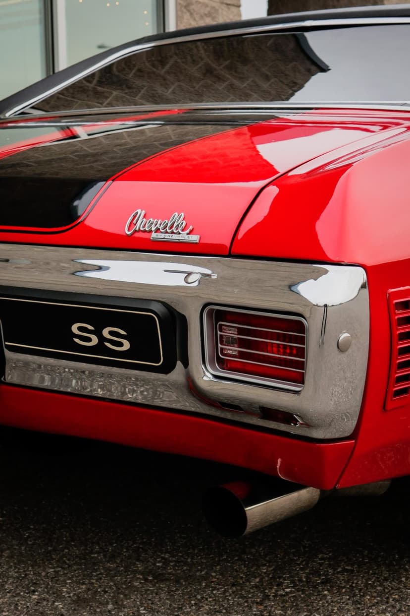 Red 1970 Chevelle SS rear with black racing stripes, chrome bumper, and silver SS emblem detail.