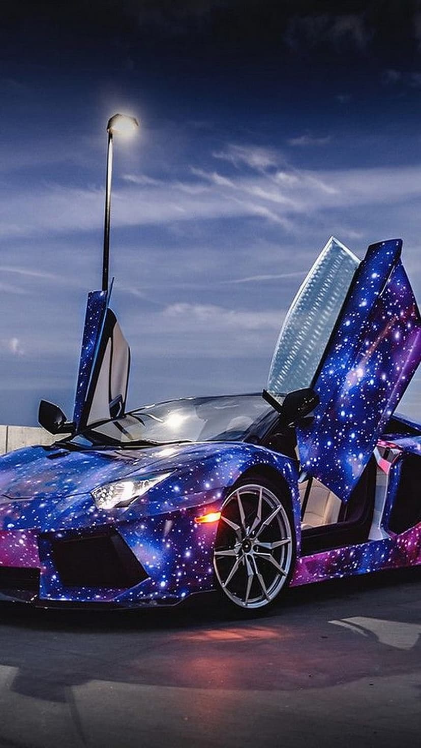 Lamborghini Aventador with a galaxy wrap and open scissor doors parked under a cloudy sky and a street lamp.