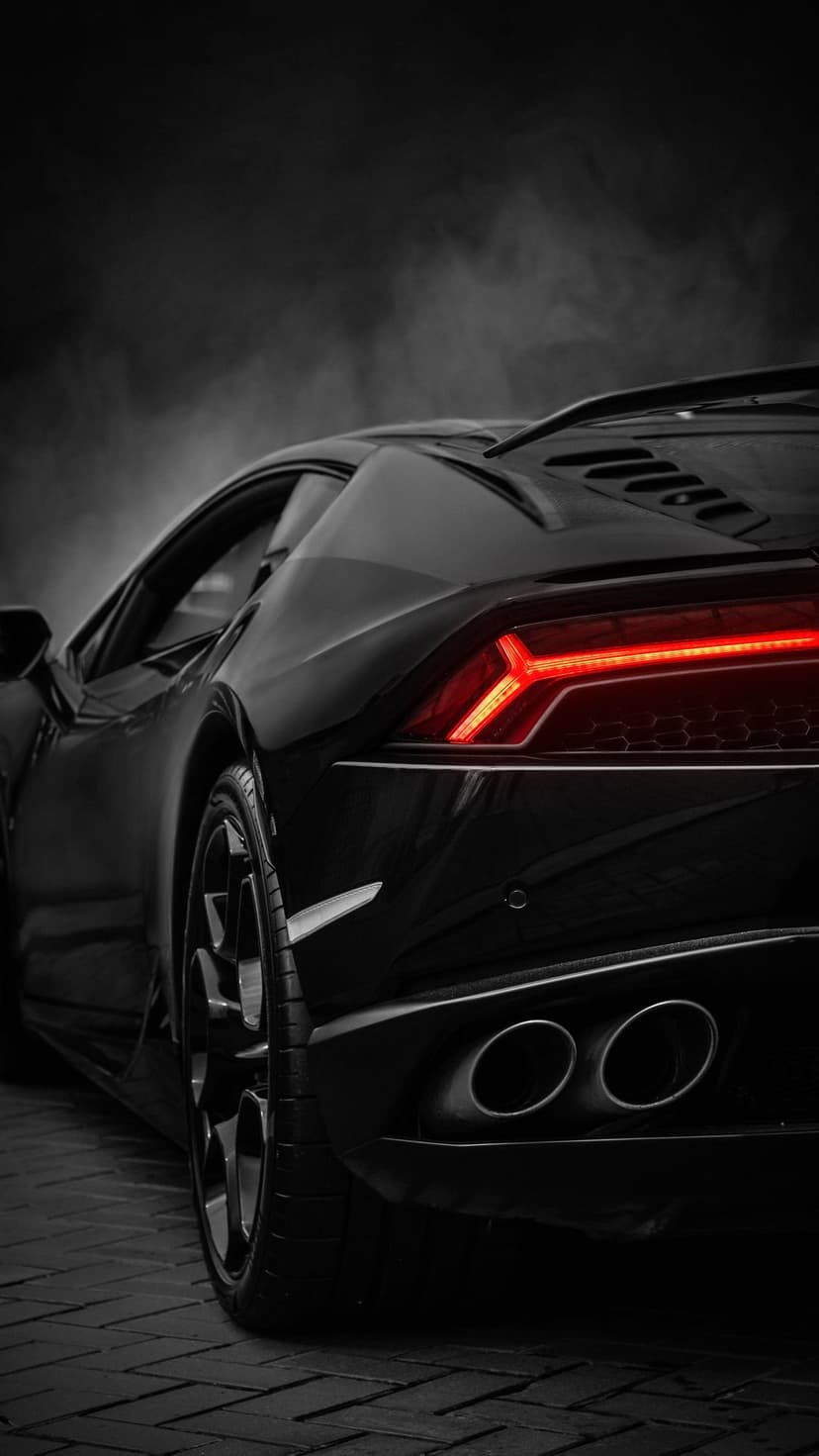 Black Lamborghini rear view with glowing red LED taillights and dual exhaust pipes on a dark smoky street.