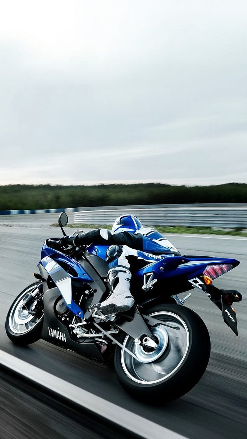 Yamaha rider in blue and white gear leans a sportbike deep into a track corner with cinematic motion blur.