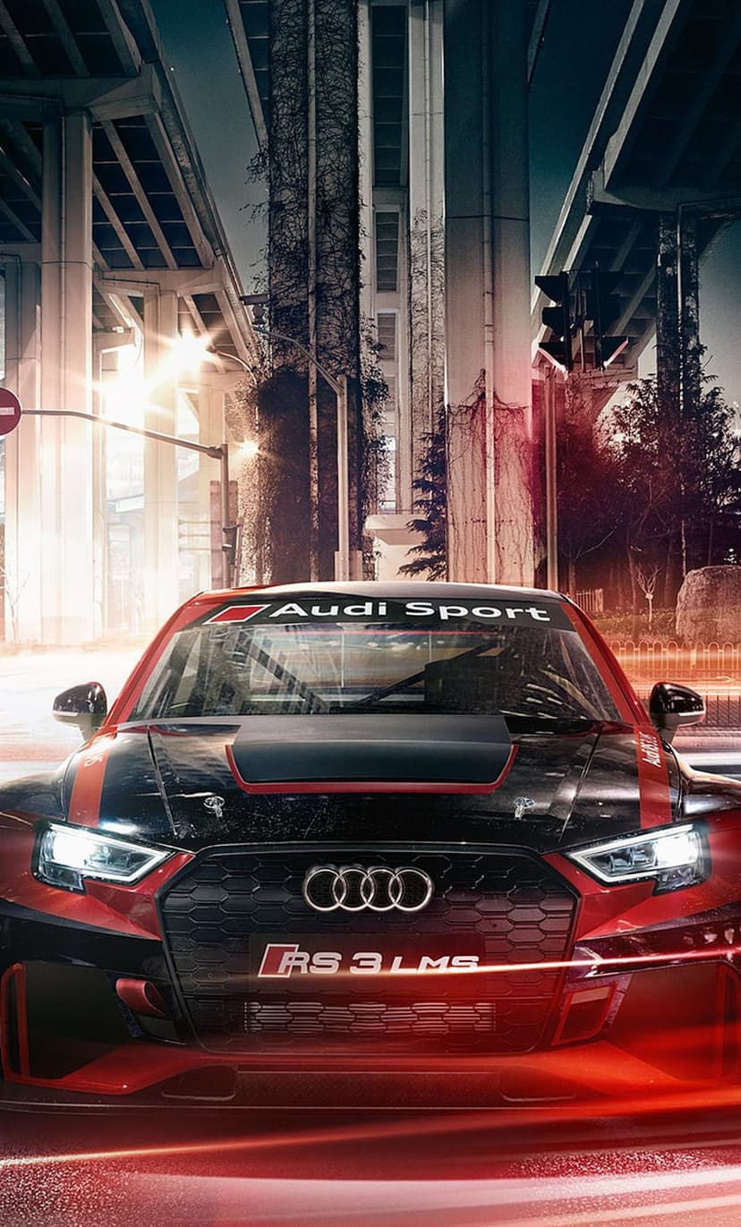 Audi RS3 LMS race car with red and black livery parked on a dark city street illuminated by golden urban lights.