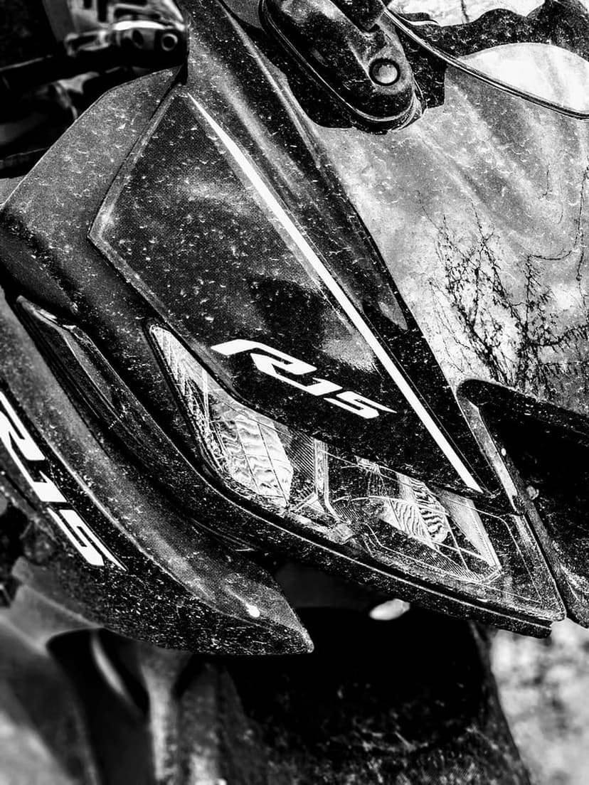 Yamaha R15 motorcycle headlight and dusty front fairing shown in a sharp black and white close-up photograph.