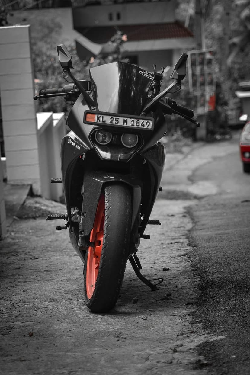 KTM motorcycle with a bright orange front wheel and black chassis parked on a paved street at a close-up angle.