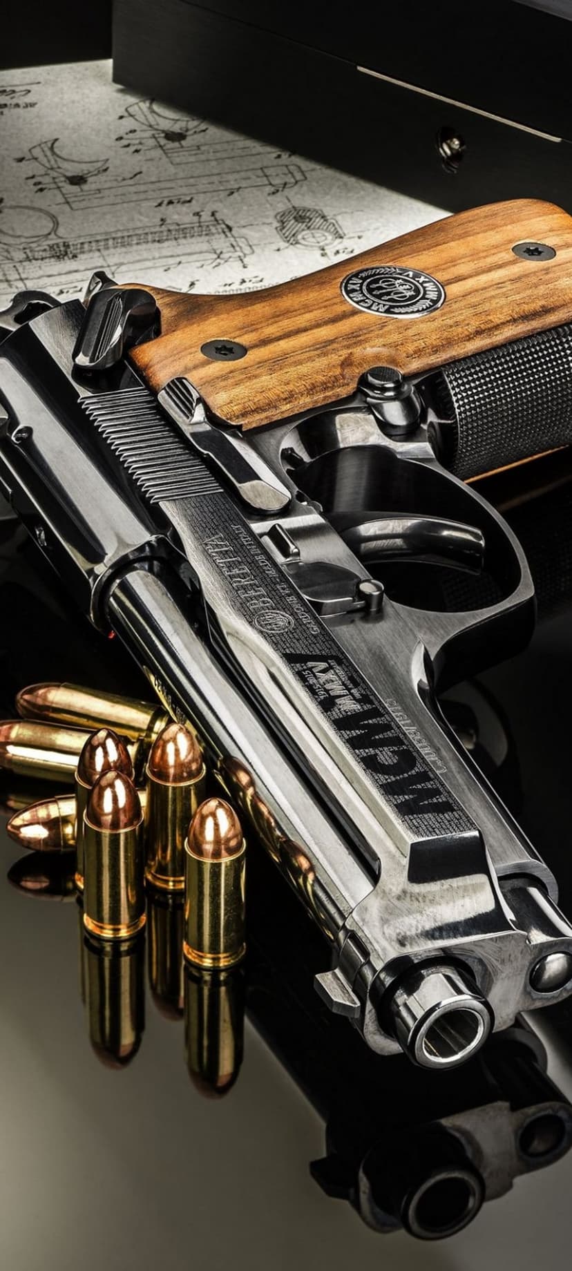 Beretta pistol with wood grips rests on black glass beside brass bullets and paper technical schematics.