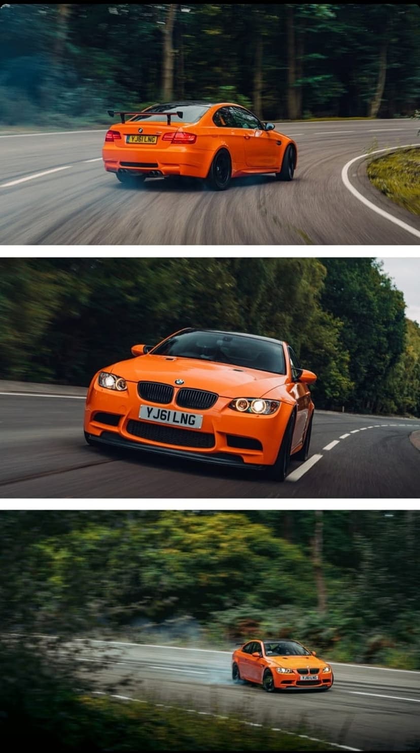Orange BMW M3 drifting on a winding forest road with white tire smoke and blurred green trees in the background.