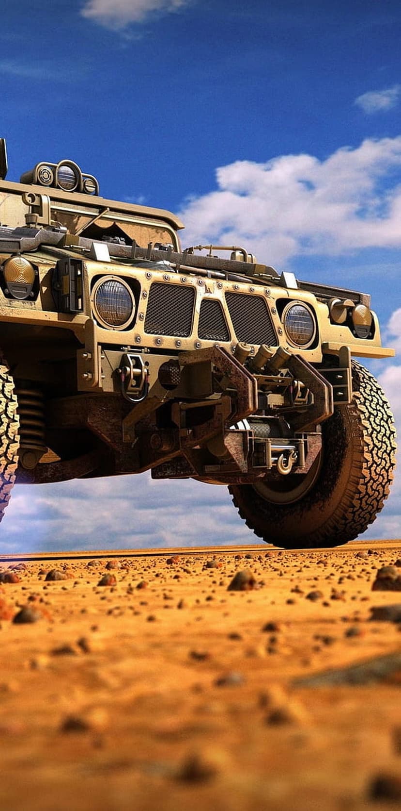 Tan military Humvee with heavy-duty tires drives over golden desert sand under a bright blue cloudy sky.