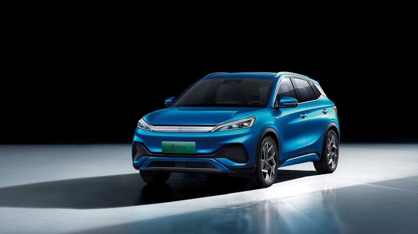 Blue electric SUV with metallic paint and silver accents parked in a dark studio with bright floor reflections.