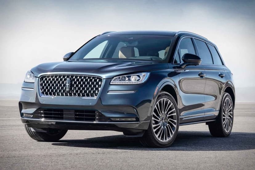 Dark blue Lincoln Corsair SUV with a chrome grille parked on a vast grey paved surface under a bright sky.