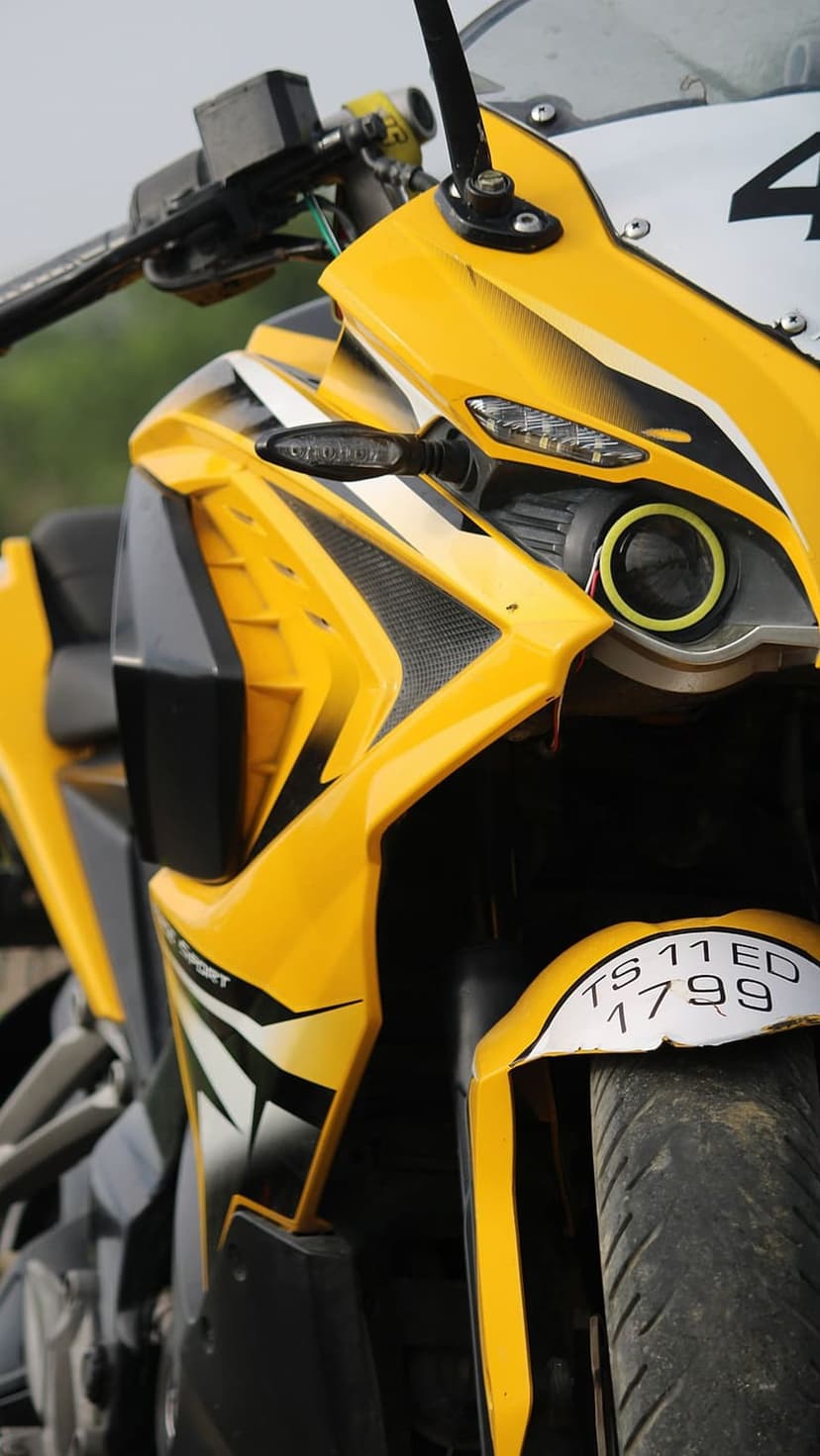 Yellow sport motorcycle front fairing featuring a halo headlight and license plate in a vertical close-up shot.
