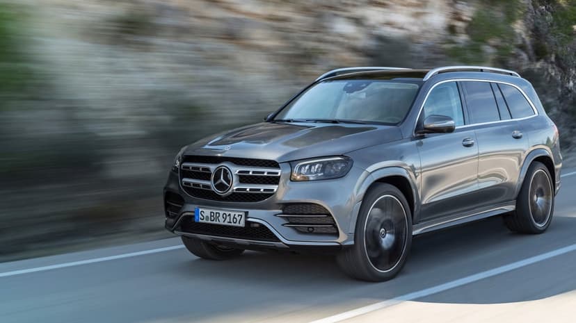 Grey Mercedes-Benz SUV driving on a road with motion blurred background and sharp metallic details.
