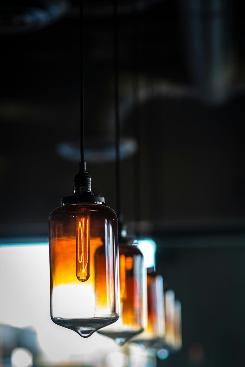 Amber Edison bulbs hanging in a row with glowing wire filaments against a dark, blurred background.