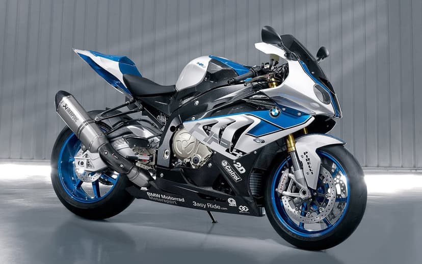 BMW HP4 sportbike with blue rims and carbon fiber bodywork against a grey studio wall background.