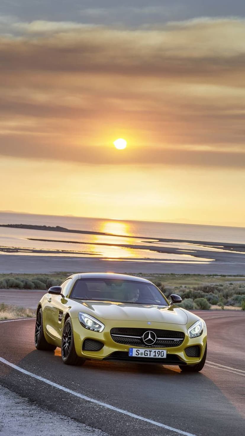 Yellow Mercedes-AMG GT S sports car driving on a coastal road during a golden sunset with ocean waves in the distance.