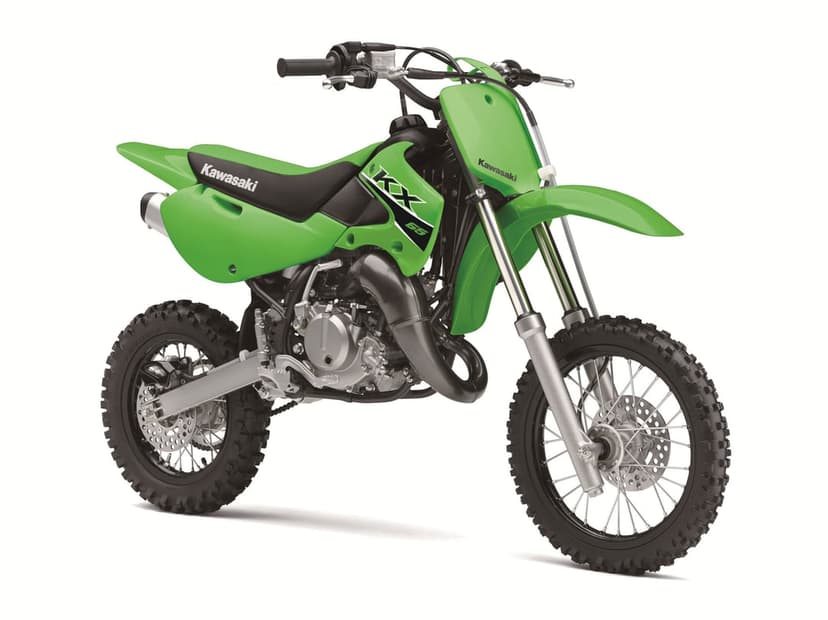 Green Kawasaki KX 65 dirt bike with knobby tires and silver mechanical parts against a solid white background.