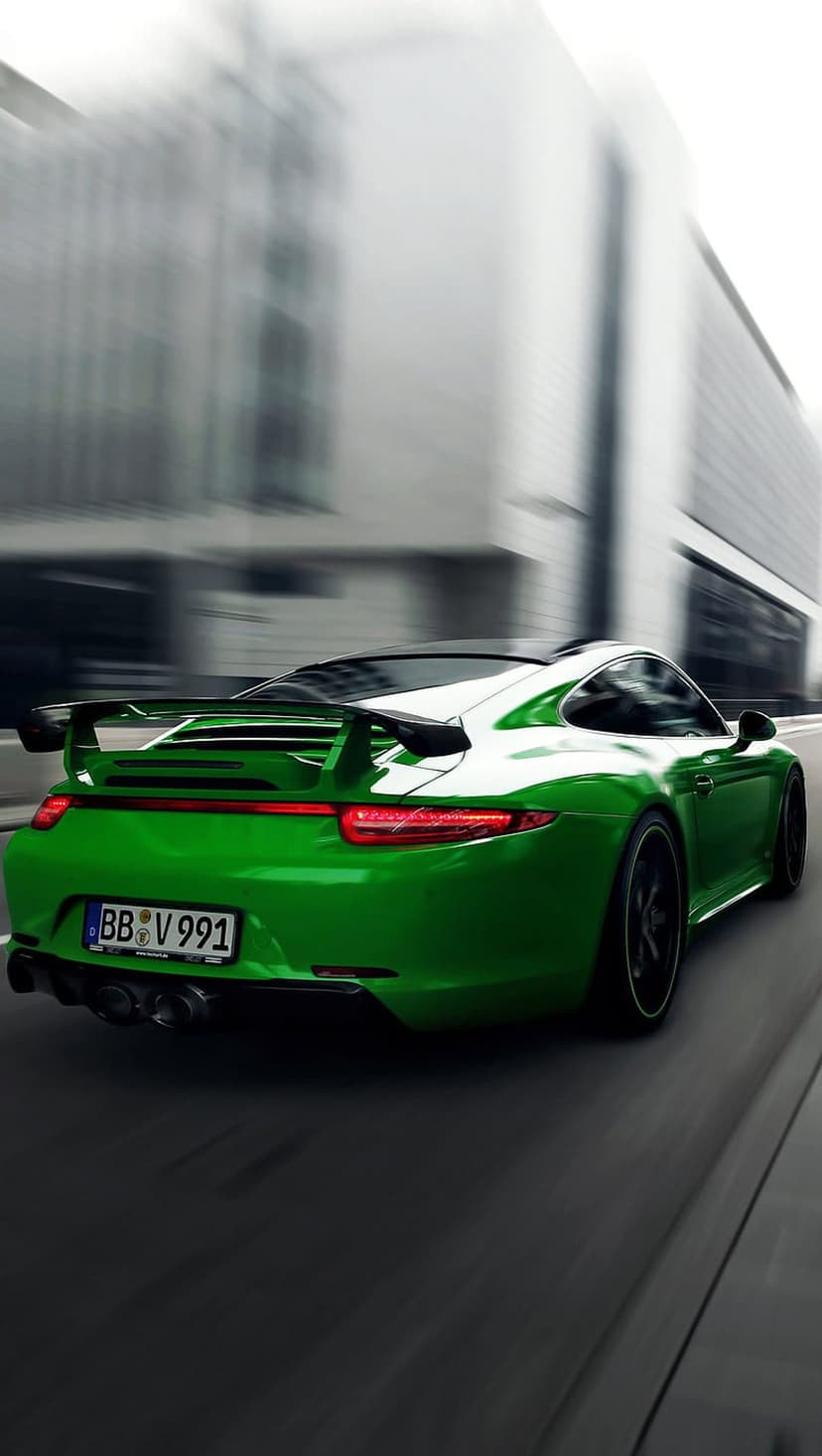 Green Porsche 911 racing through blurred city streets with glowing taillights and a prominent rear spoiler.