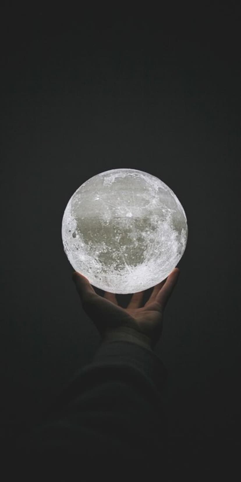Glowing sky lanterns ascend over a lone silhouette standing near a forest under a vivid gradient sunset sky.