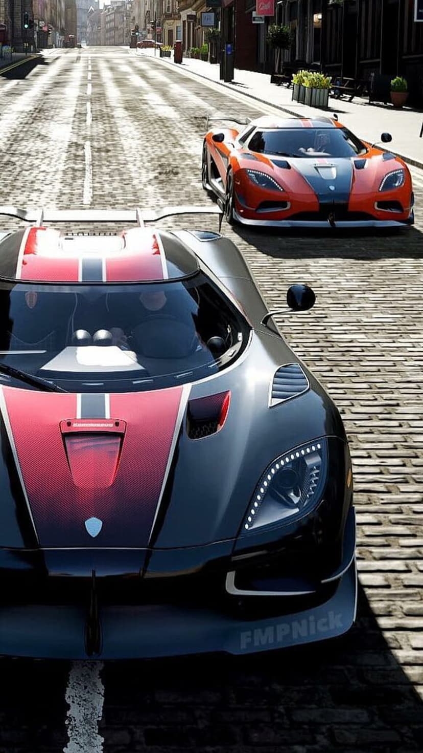 Black and red Koenigsegg CCXR racing on a cobblestone road past historic buildings in bright daylight.