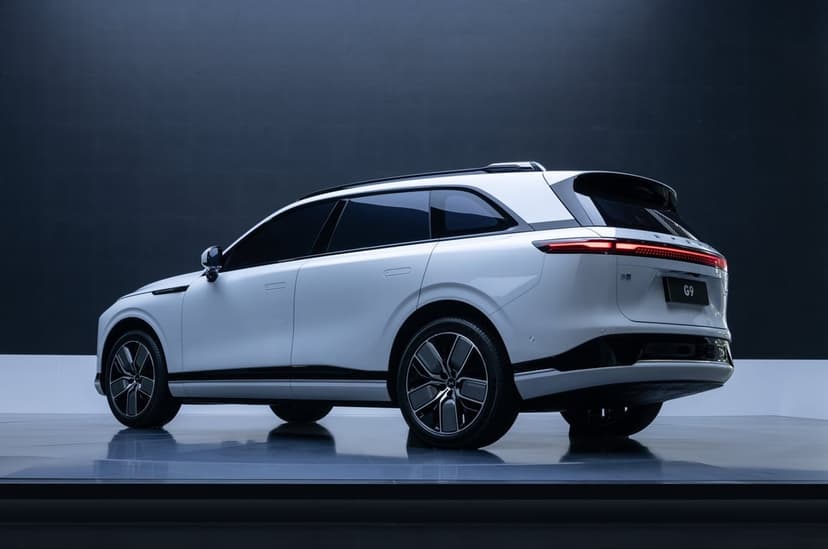 White XPENG G9 electric SUV with a red rear light bar in a dark studio with a glossy reflective floor.