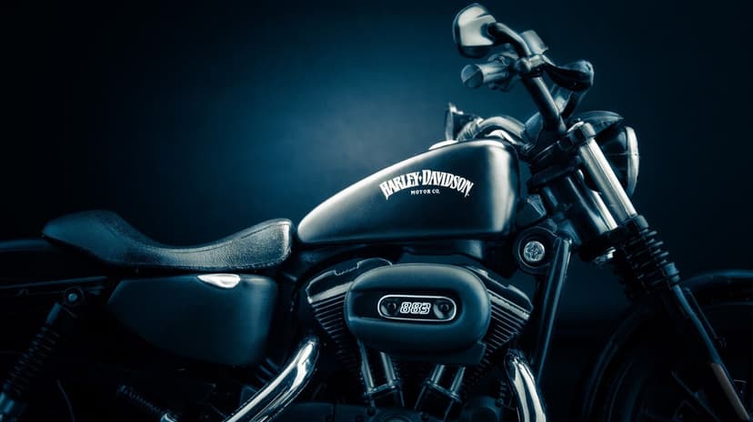 Matte black Harley-Davidson fuel tank and 883 engine badge in dramatic dark blue atmospheric lighting.