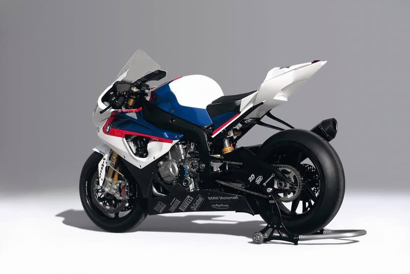 BMW S1000RR racing motorcycle in white blue and red on a rear stand against a grey studio background.