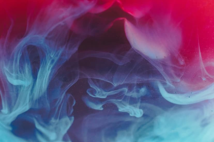 Blue and pink smoke plumes intertwine against a black background with soft fluid textures and organic swirls.