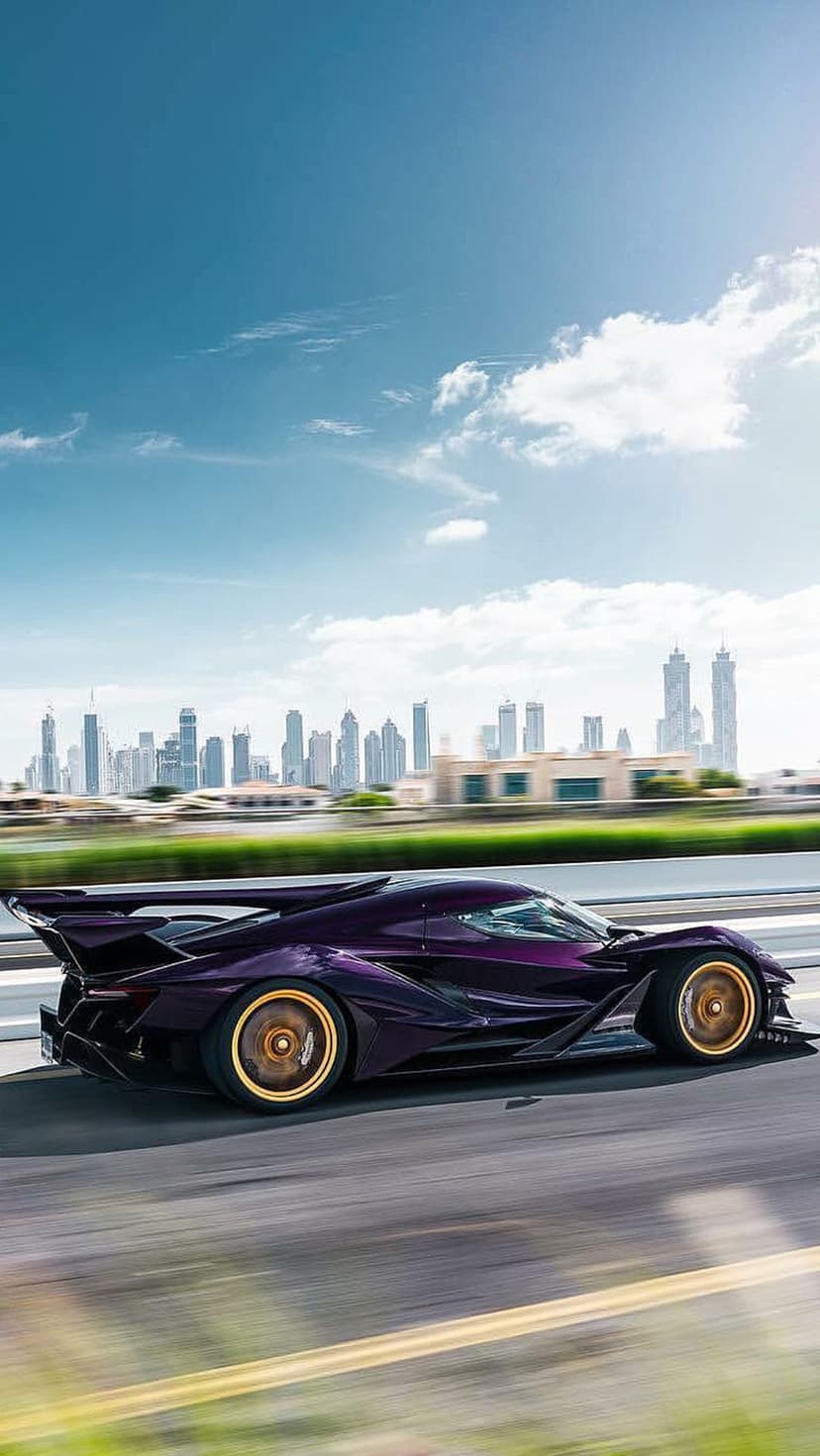 Purple hypercar with gold wheels racing on a highway with the Dubai skyline and Burj Khalifa under a blue sky.